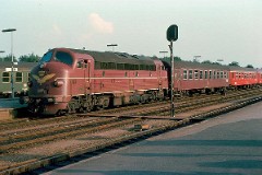 DSB MY 1109 photographed at the railway station in Fredericia July 1975.  The MY class was built by Nydquist & Holm AB (NOHAB) in Sweden licensed by General Motors. Danish subsuppliers (Frichs and Thrige) took part in the production. A1A-A1A. Dieselelectric. MY 1101 - 1105 was supplied with a General Motor 16-cyl. diesel engine performing 1.700 hp. The diesel engine in MY 1106 - 1144 was performing 1.950 hp - MY 1145 - 1159 1700 hp. Max speed 133 km/h - 83 mph. Length 18 900 mm. Weight 101,6 metric tonnes. MY 1109 was put in service in 1956. It was taken out of service in 1985.
